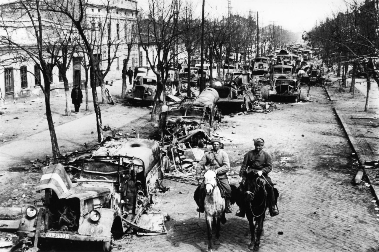 Советские солдаты едут по улице освобожденной Одессы, забитой брошенной немцами техникой. Фото — Дмитрий Бальтерманц. Апрель 1944