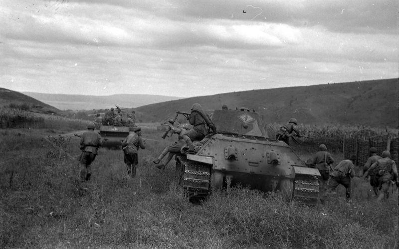Бойцы советского танкового десанта спрыгивают с брони танка Т-34 во время боя за населенный пункт на Кавказе. На втором плане танк КВ-1. Танки из 52-й танковой бригады, Закавквзский фронт.